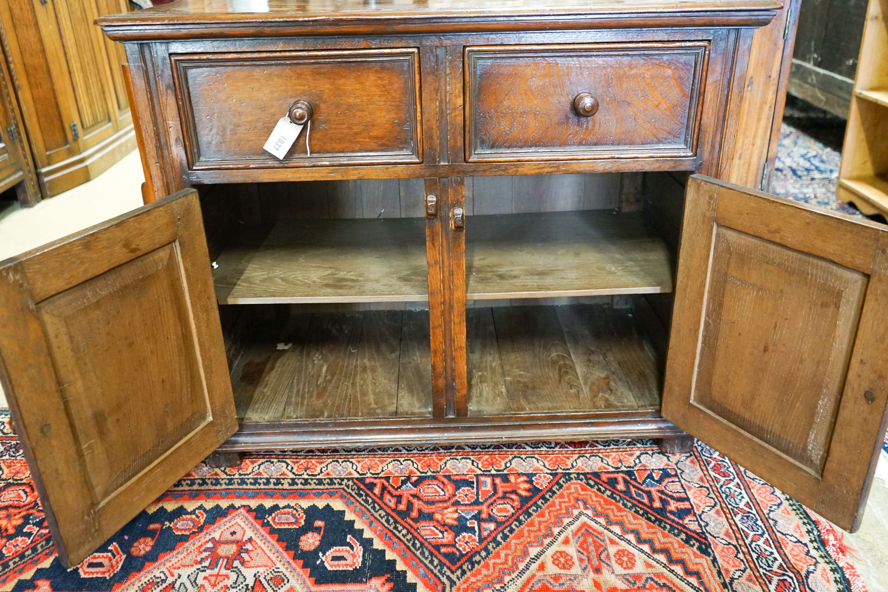 A 17th century style carved and panelled oak cupboard